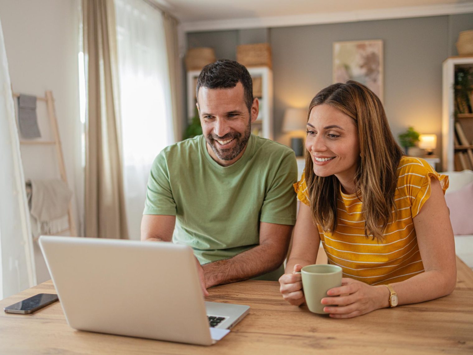 A couple sitting at their kitchen table with a laptop applying for a VA home loan.