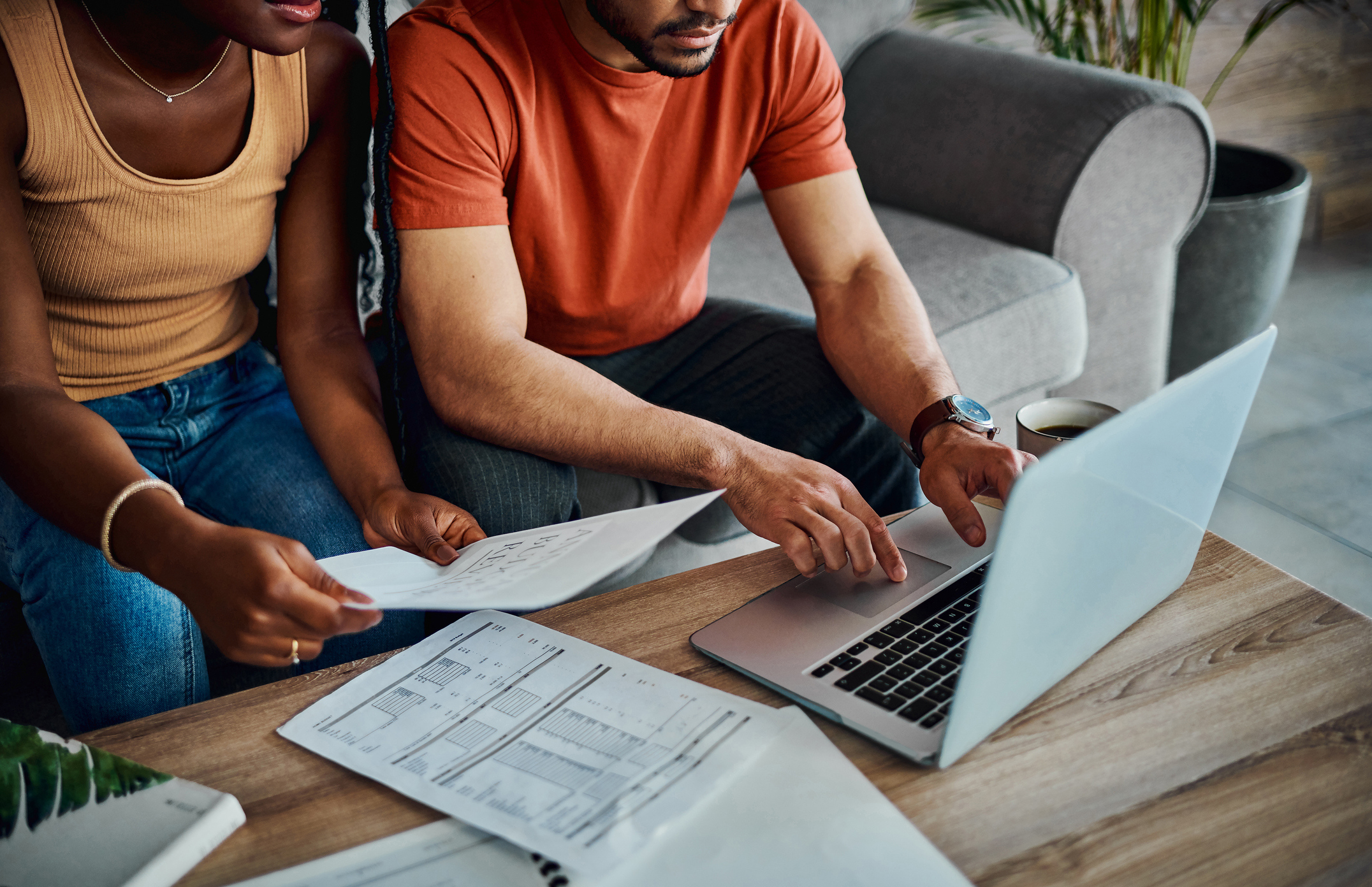 A couple reviewing tax documents and working on a laptop in their living room.