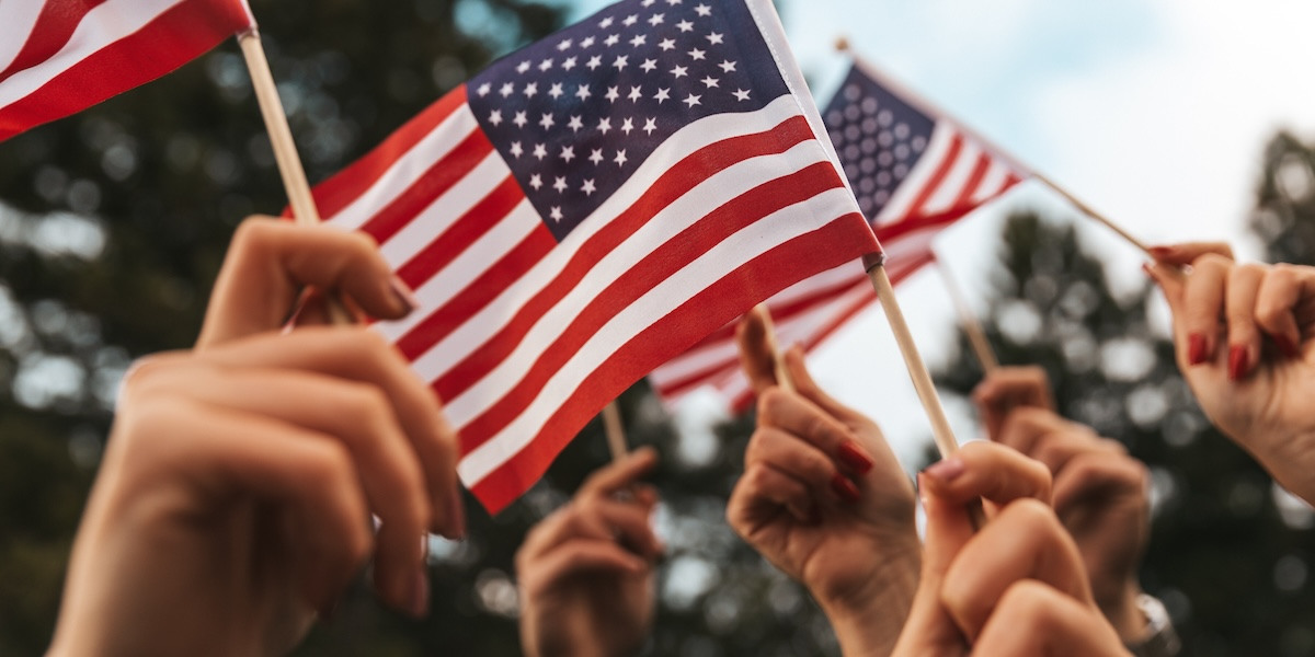 Hands waving small American flags in the air.